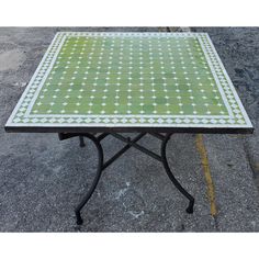 a table that is sitting on the ground in front of some concrete pavement with white and green designs