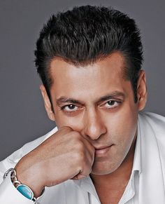 the man is posing with his hand on his chin and looking at the camera while wearing a white shirt