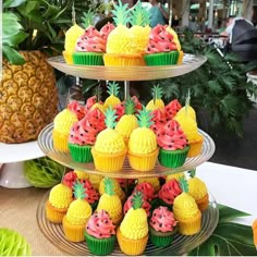 three tiered trays filled with cupcakes and pineapples