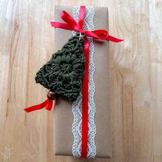 a wrapped present with a crochet christmas tree decoration on it's side