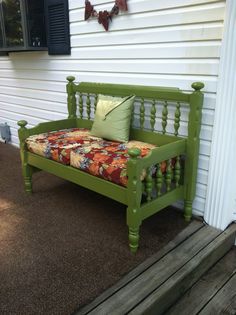 a green bench sitting on the side of a house