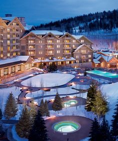 the resort is lit up at night with lights on and snow covered ground around it