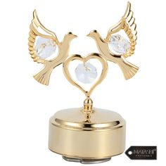 two gold birds on top of a heart shaped box with crystal hearts in the center