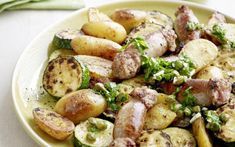 a white plate topped with potatoes and broccoli next to a bowl of sauce