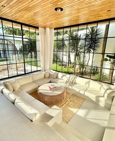 a living room filled with lots of white furniture and large windows overlooking the pool area