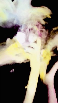 a blurry image of hands holding something yellow and white in front of black background