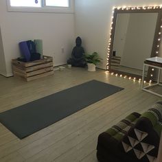 a yoga mat in the middle of a living room with lights on it and a buddha statue