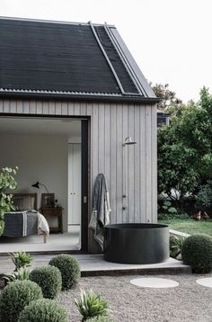 an outdoor bathtub sits in the middle of a graveled area with potted plants