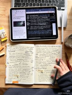 an open notebook with writing on it next to a laptop