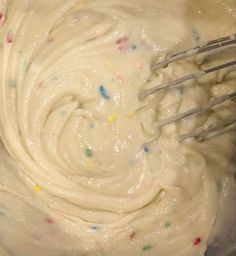 a mixing bowl filled with white frosting and sprinkles