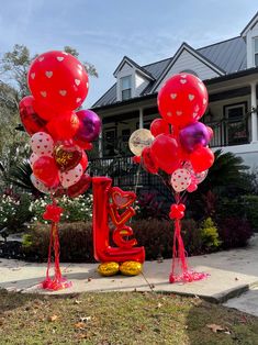 some balloons are in the shape of letters and hearts on a lawn near a house