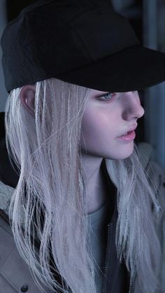 a woman with long white hair wearing a black baseball cap and looking off to the side