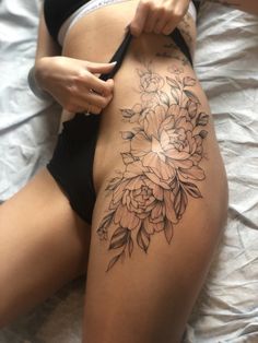 a woman's thigh with flowers on it and leaves around the thighs, as well as an arm tattoo