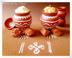 two clay pots sitting on top of a table with writing in the sand next to them