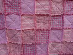 a pink and white quilt with squares on it