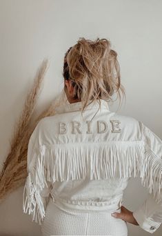 the back of a woman's jacket that says bride with fringes on it