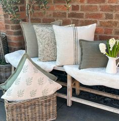 a bunch of pillows sitting on a bench next to a basket with flowers in it