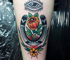 an eye and flower tattoo on the leg