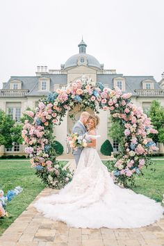 a bride and groom standing in front of a wedding arch with pink flowers on it