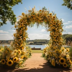 an outdoor wedding ceremony with sunflowers and greenery on the aisle to the water