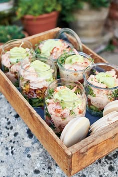 a wooden tray filled with lots of food on top of a stone counter next to potted plants