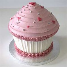 a pink cupcake with white frosting and hearts on top