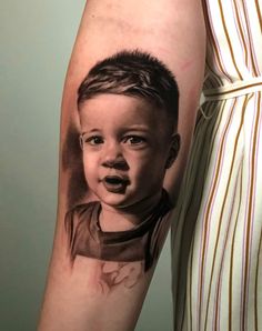 a man's arm with a tattoo of a young boy on the left forearm