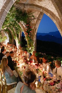 a group of people sitting around a table with flowers and candles in front of them