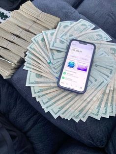 a cell phone sitting on top of a pile of money next to stacks of $ 100 bills