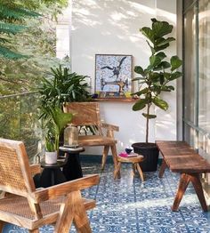 an outdoor patio with wooden chairs and potted plants on the side wall, next to a blue tiled floor