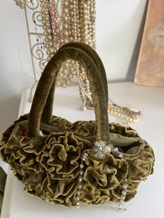 "Plush luxurious heavy olive velvet handmade flower purse. This one of a kind piece will never go out of style. Wear fancy or with jeans.  I handmade each velvet flower, some are a drop bigger or smaller than others, to create a super full bloom look. The flowers go all the way around the bag. It is adorned with a vintage jewelry chain necklace that drapes off the side handle. This purse is durable and will sit table top to be a conversation piece.  Comes with a pretty drawstring with ribbon dus Olive Velvet, Velvet Handbag, Olive Green Velvet, Velvet Flower, Flower Purses, Velvet Purse, Velvet Flowers, Jewelry Chain, Art To Wear