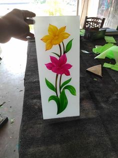 a person is painting flowers on a piece of paper