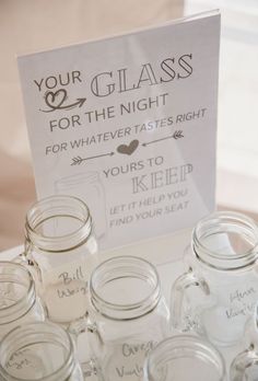 there are many mason jars on the table with a sign that says your glass for the night