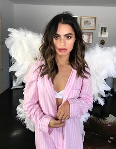 a woman with angel wings on her back in a pink robe and white bra top