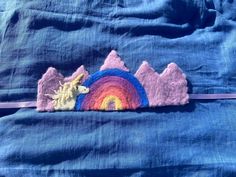 there is a piece of felt with a unicorn on it and a rainbow in the background