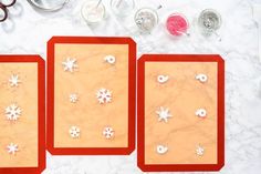 three red trays with snowflakes on them next to scissors and other items