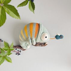 a crocheted stuffed animal sitting on top of a branch next to a plant