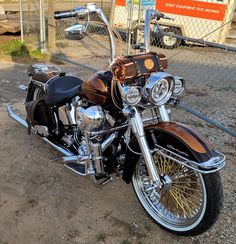 a black and brown motorcycle parked next to a fence