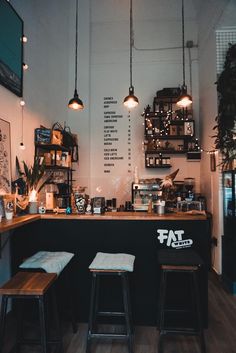 the inside of a coffee shop with three stools and lights hanging from the ceiling