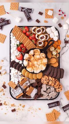 a platter filled with crackers, marshmallows, and other snacks