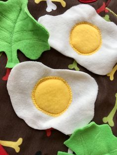 two fried eggs on a brown and green fabric with yellow felt appliques