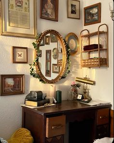 a desk with a mirror, lamp and pictures on the wall above it in a room