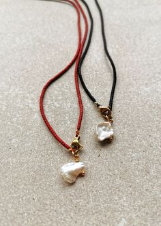 two necklaces on a white surface with red string