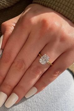 a woman's hand with white manies and a diamond ring on her finger