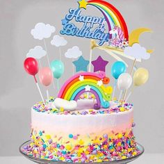 a birthday cake decorated with balloons and rainbows