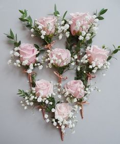 pink roses and white baby's breath are arranged on a gray background with greenery