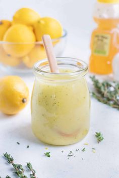 a jar filled with liquid next to lemons and herbs