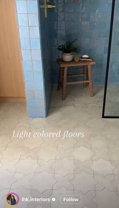 a blue tiled bathroom with a stool and mirror