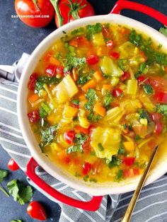 a white bowl filled with vegetable soup next to some tomatoes and parsley on the side