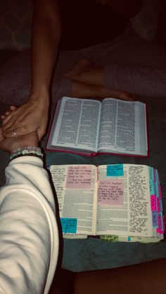 two people holding hands over an open book